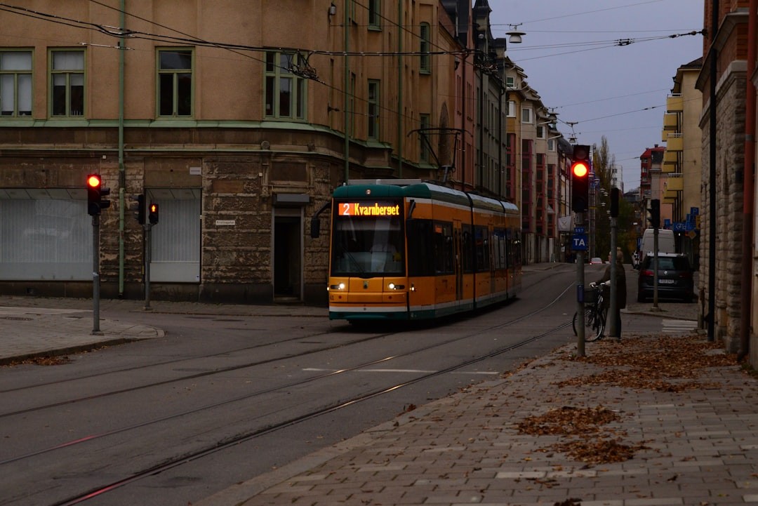 a yellow and green train traveling down a street next to tall buildings